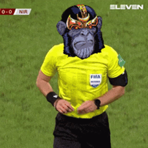 A Referee Wearing A Yellow Shirt With A Monkey Face On His Face GIF