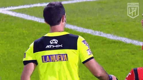 A Referee Wearing A Yellow Shirt With The Word La Nueva On It GIF