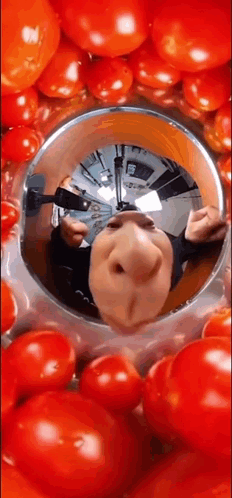 A Reflection Of A Person 'S Face In A Bowl Of Tomatoes . GIF
