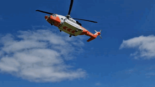 A Rescue Helicopter From The High Coast Guard Is Flying In The Sky GIF