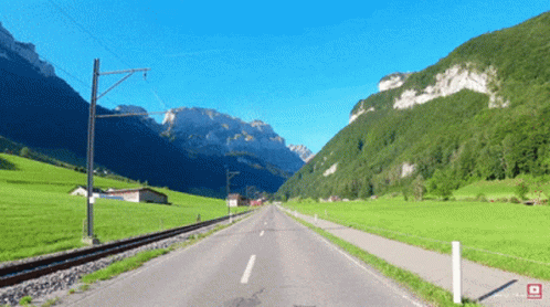 A Road Going Through A Valley With Mountains On The Horizon GIF