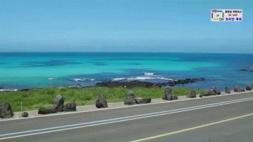 A Road Going Towards The Ocean With A Sign That Says 4K Uhd On It GIF