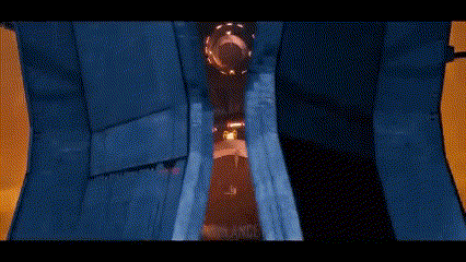 A Robot Is Standing In A Dark Room With A Blue Curtain . GIF