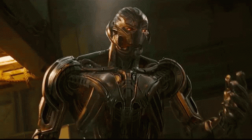 A Robot Is Standing In A Dark Room With A Yellow Light Behind It GIF