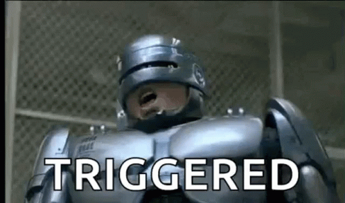 A Robot Is Standing In Front Of A Fence And Says `` Triggered '' . GIF