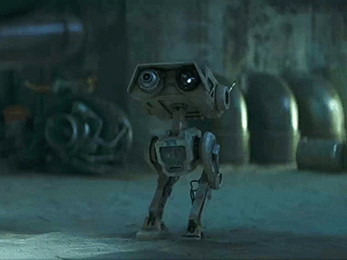 A Robot With A Camera On It 'S Head Is Walking On The Ground In A Dark Room . GIF