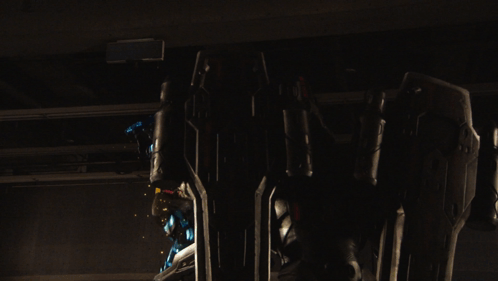 A Robot With A Glowing Blue Armor Is Standing Next To A Large Shield GIF