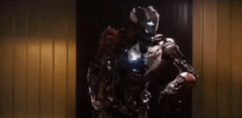 A Robot With A Helmet On Is Standing In A Doorway . GIF