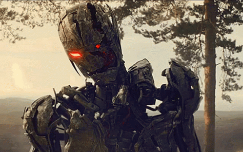 A Robot With Red Eyes Is Standing In Front Of A Tree GIF