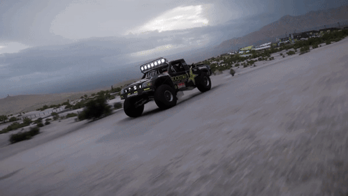 A Rockstar Truck Is Driving Down A Sandy Road GIF