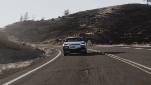 A Rolls Royce Car Is Driving Down A Winding Road GIF