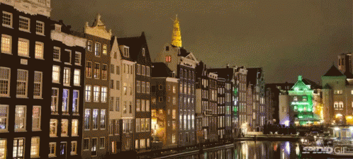 A Row Of Buildings Next To A Body Of Water With A Green Building In The Foreground GIF