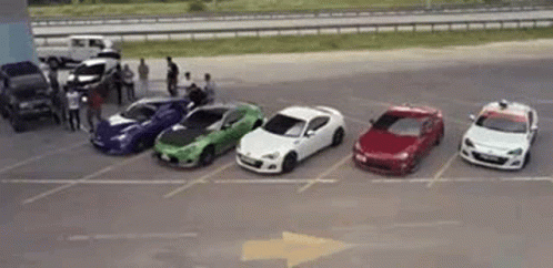 A Row Of Cars Are Parked In A Parking Lot Next To Each Other . GIF