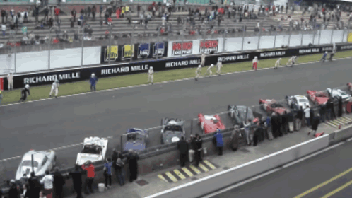 A Row Of Cars Are Parked On A Race Track With Richard Mille Advertisements GIF