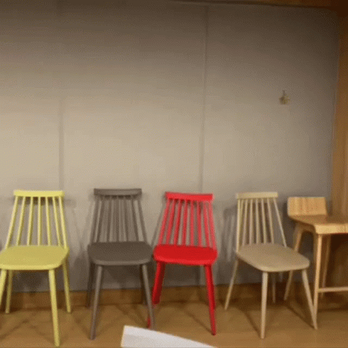 A Row Of Chairs Of Different Colors Are Lined Up In A Room GIF