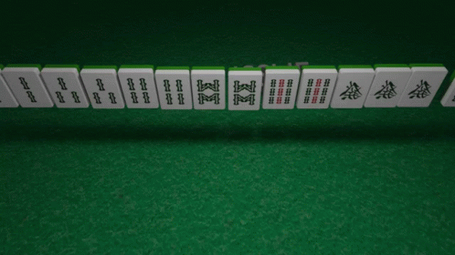 A Row Of Chinese Mahjong Tiles On A Green Mat GIF