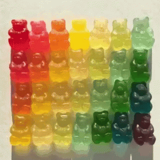 A Row Of Colorful Gummy Bears Are Lined Up In A Row GIF
