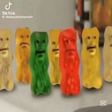 A Row Of Gummy Bears With Faces On Them Are Sitting On A Table . GIF