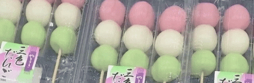 A Row Of Pink , White , And Green Balls On Sticks In Plastic Containers . GIF