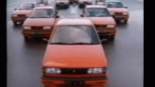 A Row Of Red Cars Are Driving Down A Street In A Blurry Photo . GIF