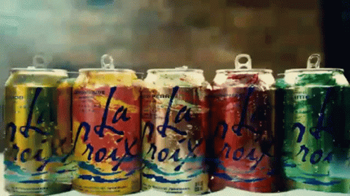 A Row Of Soda Cans With One That Says ' La ' On It GIF