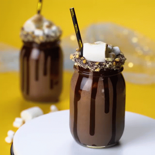A S'mores Milkshake In A Mason Jar With Chocolate Sauce And Marshmallows GIF