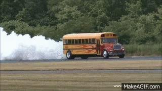 A School Bus Driving Down A Road With Smoke Coming Out Of It GIF