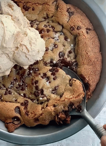 A Scoop Of Ice Cream Is Being Poured On Top Of A Cookie GIF