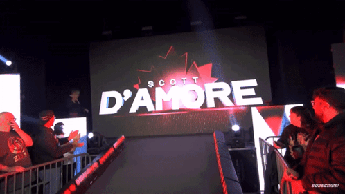 A Scott D' Amore Sign Is Displayed On A Large Screen GIF
