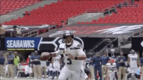 A Seahawks Football Player Is Running With A Ball GIF