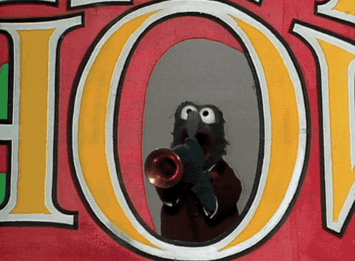 a sesame street character is playing a trumpet in front of a sign that says hot