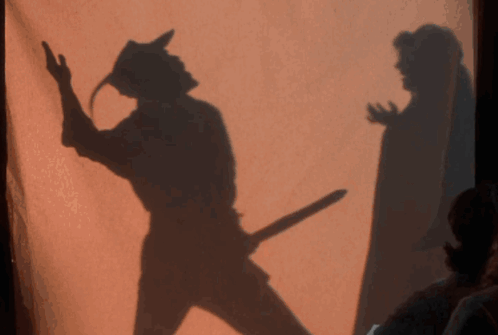A Shadow Of A Man Holding A Sword Is Behind A Woman GIF