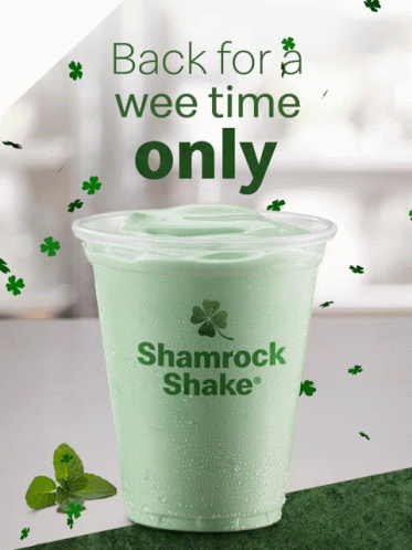 A Shamrock Shake In A Plastic Cup With Shamrocks Around It GIF