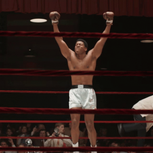 A Shirtless Boxer In A Ring With His Arms Up GIF