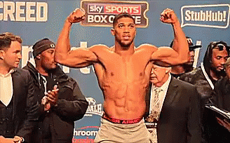 A Shirtless Boxer Is Flexing His Muscles In Front Of A Sign That Says Sky Sports Box Office GIF
