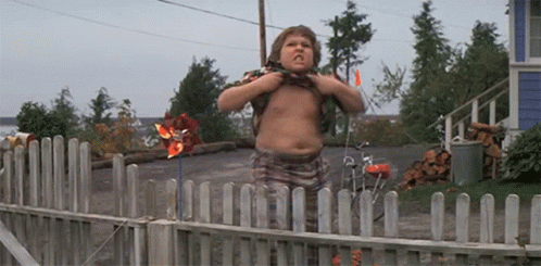 A Shirtless Boy Stands In Front Of A Wooden Fence GIF