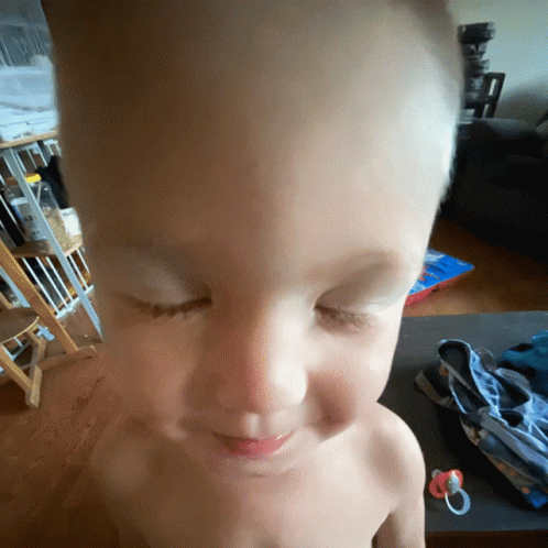 a shirtless child with his eyes closed and a pacifier