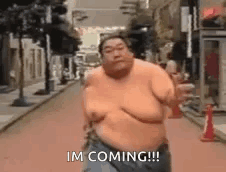 A Shirtless Fat Man Is Running Down A Street And Saying `` Im Coming '' . GIF