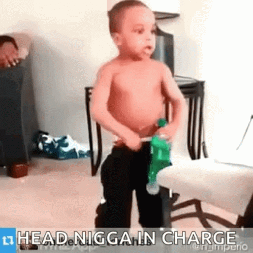 A Shirtless Little Boy Is Standing Next To A Chair And Holding A Bottle Of Water . GIF