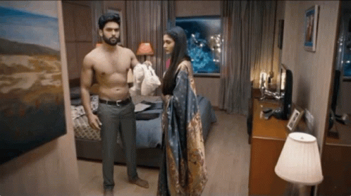 A Shirtless Man And A Woman Are Standing In A Bedroom GIF