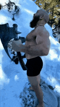 A Shirtless Man Holding A Large Axe In The Snow GIF