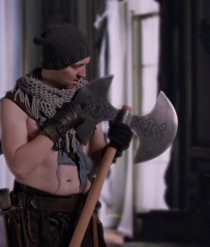 A Shirtless Man Holding A Large Axe With A Celtic Design On It GIF