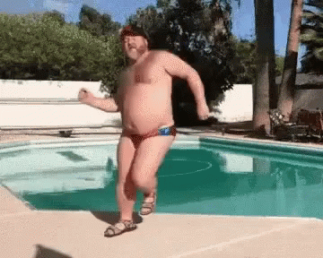 A Shirtless Man In A Bathing Suit Is Dancing In A Pool . GIF
