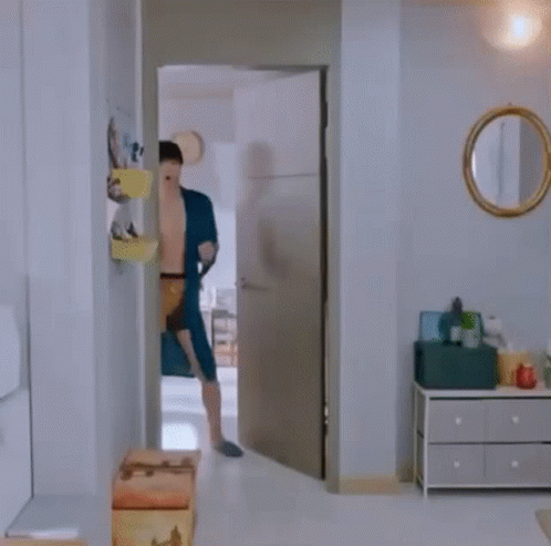 A Shirtless Man In A Blue Robe And Underwear Is Dancing In A Room . GIF