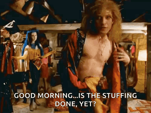 a shirtless man in a robe is standing in a room with a woman standing behind him .