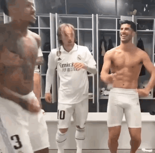 A Shirtless Man In A White Emirates Fly Better Shirt Stands In A Locker Room GIF
