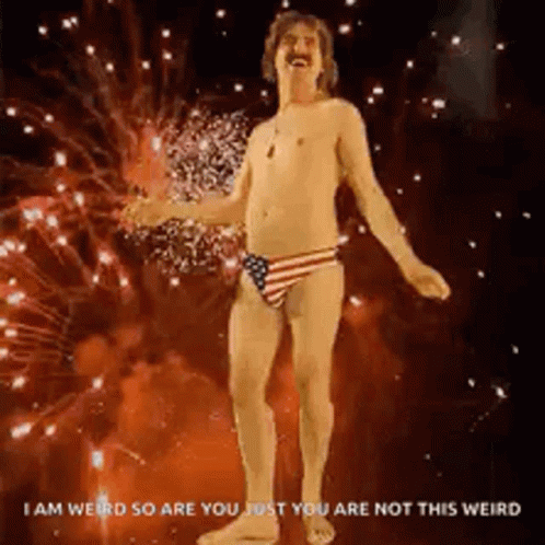 A Shirtless Man In An American Flag Underwear Is Dancing In Front Of Fireworks . GIF