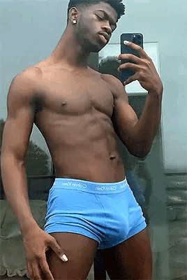A Shirtless Man In Blue Underwear Is Taking A Selfie With His Cell Phone In Front Of A Mirror . GIF