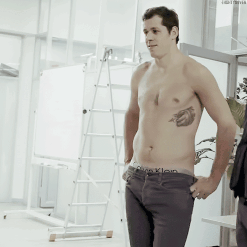a shirtless man in calvin klein underwear stands in a room