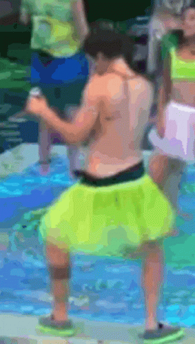 A Shirtless Man In Neon Yellow Shorts Is Dancing In The Water GIF